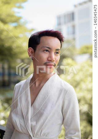 Vertical close up portrait of non-binary gay Thai man looking away on outdoor balcony Vertical close up portrait of non-binary gay Thai man looking away on outdoor balcony 140345475
