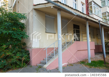 Building exterior with ramp and shaded plants in urban setting during daylight hours Building exterior with ramp and shaded plants in urban setting during daylight hours 140345566