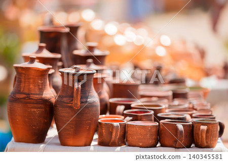 Handcrafted pottery displayed at a local market with warm sunlight illuminating the vibrant colors Handcrafted pottery displayed at a local market with warm sunlight illuminating the vibrant colors 140345581