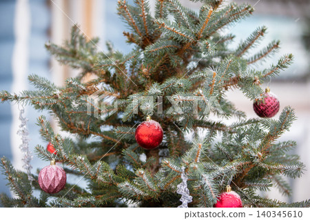 Beautifully decorated Christmas tree with red ornaments standing outdoors in a winter setting Beautifully decorated Christmas tree with red ornaments standing outdoors in a winter setting 140345610
