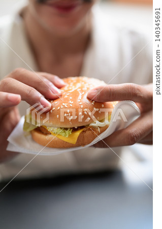 Macro Close Up of Cheeseburger Held with Paper Napkin Macro Close Up of Cheeseburger Held with Paper Napkin 140345691