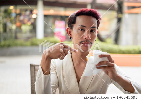 Thai Non-Binary Gay Man Pointing at Burger Outside Cafe Thai Non-Binary Gay Man Pointing at Burger Outside Cafe 140345695