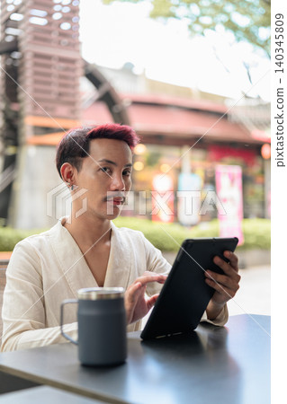 Thai Non-Binary Gay Man Vertical Portrait Looking At Camera with Tablet Thai Non-Binary Gay Man Vertical Portrait Looking At Camera with Tablet 140345809