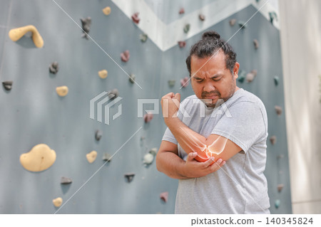 Overweight Asian man suffering from elbow joint pain with glowing bone anatomy graphic overlay after rock climbing exercise. Sports injury, arthritis and muscle inflammation medical healthcare concept Overweight Asian man suffering from elbow joint pain with glowing bone anatomy graphic overlay after rock climbing exercise. Sports injury, arthritis and muscle inflammation medical healthcare concept 140345824