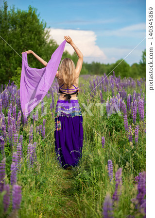 Woman dancing gracefully in a field of purple flowers under a blue sky 140345869