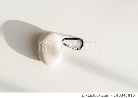 Beige wireless earbuds case with carabiner on white background Beige wireless earbuds case with carabiner on white background 140345910
