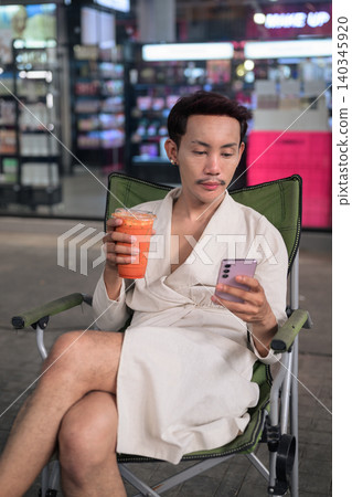 Thai Non-Binary Gay Man Texting and Drinking Iced Tea Vertical Portrait Thai Non-Binary Gay Man Texting and Drinking Iced Tea Vertical Portrait 140345920