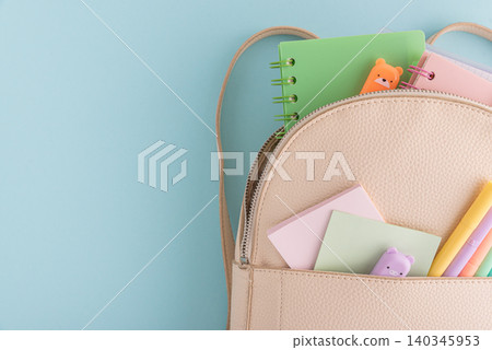 Beige backpack filled with school supplies and stationery, back to school Beige backpack filled with school supplies and stationery, back to school 140345953
