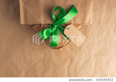 Craft gift box with green ribbon and blank tag in a bag Craft gift box with green ribbon and blank tag in a bag 140345972