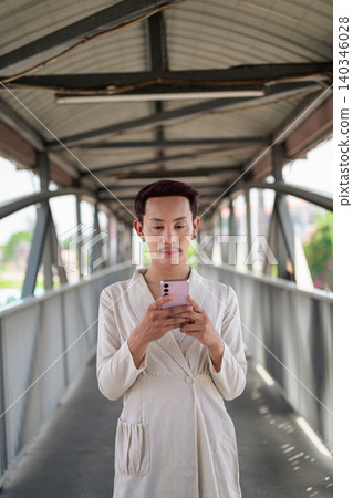 Vertical Portrait of Thai Non-Binary Gay Man Texting on Footbridge Vertical Portrait of Thai Non-Binary Gay Man Texting on Footbridge 140346028