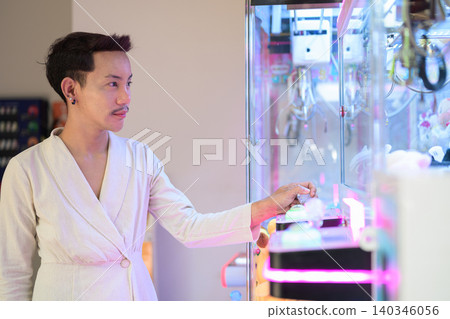 Thai Non-Binary Gay Man Controlling Arcade Claw Machine Thai Non-Binary Gay Man Controlling Arcade Claw Machine 140346056