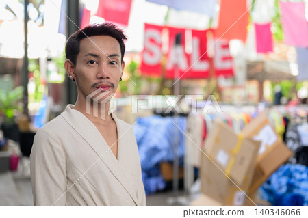 Thai Non-Binary Gay Man Looking at Camera at Street Market Sale Thai Non-Binary Gay Man Looking at Camera at Street Market Sale 140346066