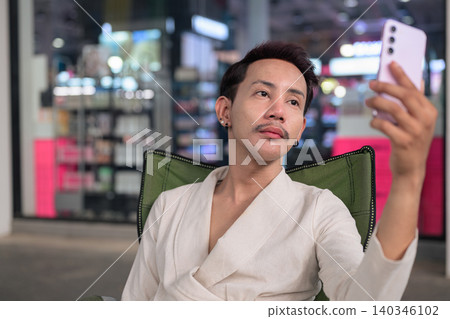 Thai Non-Binary Gay Man Taking Selfie in Folding Chair Outdoors Thai Non-Binary Gay Man Taking Selfie in Folding Chair Outdoors 140346102