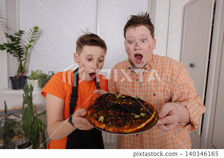 Kids excitedly react to burnt pizza while cooking together in a home kitchen during the afternoon Kids excitedly react to burnt pizza while cooking together in a home kitchen during the afternoon 140346165