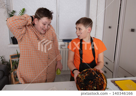 Two boys react to burnt pizza while cooking in a bright kitchen 140346166