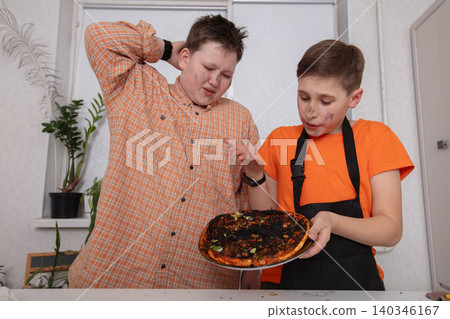 Two boys react to a burnt pizza in a kitchen setting during a cooking activity in the afternoon Two boys react to a burnt pizza in a kitchen setting during a cooking activity in the afternoon 140346167