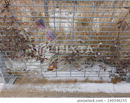 Lost sunglasses hanging on a metal grid fence Lost sunglasses hanging on a metal grid fence 140346255
