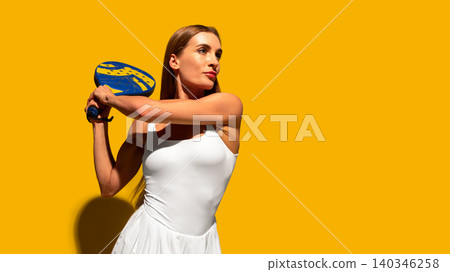 Female padel player holding racket on bright yellow studio background. Female padel player holding racket on bright yellow studio background. 140346258