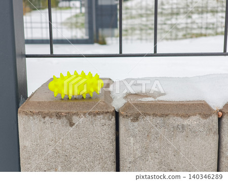 Spiky yellow massage item on snowy concrete fence Spiky yellow massage item on snowy concrete fence 140346289