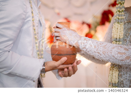 Traditional Indonesian wedding ritual with a ceremony using a clay jug. 140346324