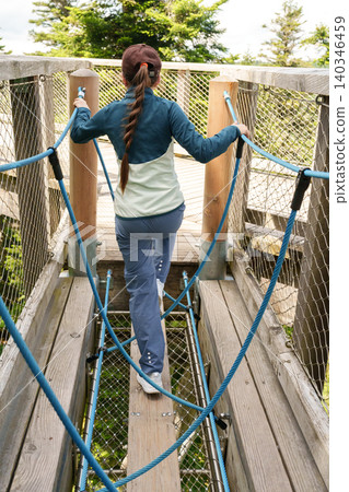 Girl climbing rope course in treetop adventure park Girl climbing rope course in treetop adventure park 140346459