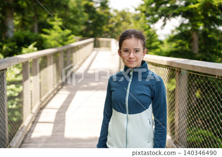 Girl walking on treetop walkway in forest adventure park 140346490