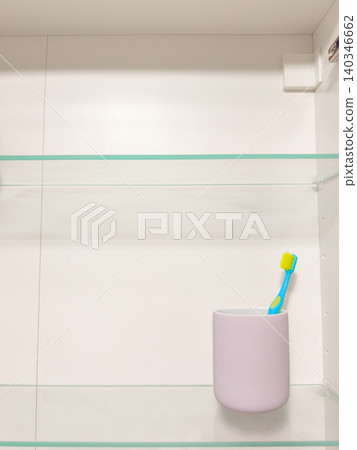 Toothbrush in a holder on a clear bathroom shelf 140346662