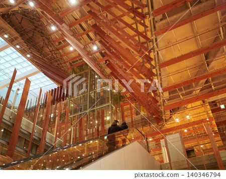 A view of the interior of Toyama Library and a woman riding an escalator. 140346794