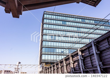 Modern buildings and railway structures stand out against the blue sky, viewed from an upward angle. 140347122