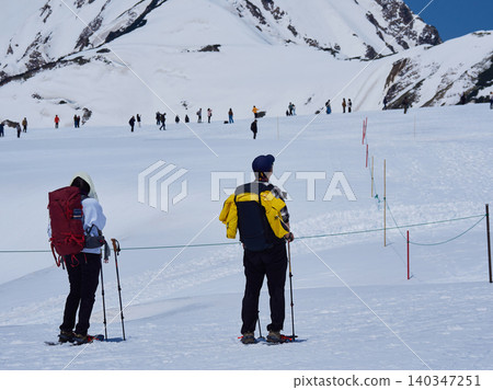 Snowy scenery and hikers at the summit of Murodo Mountain on the Tateyama Kurobe Alpine Route, a popular tourist spot. Snowy scenery and hikers at the summit of Murodo Mountain on the Tateyama Kurobe Alpine Route, a popular tourist spot. 140347251