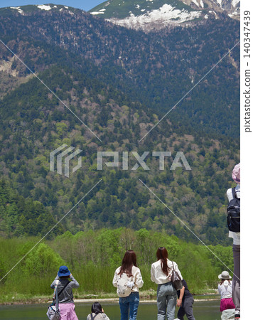Tourists enjoying the fresh greenery of Kamikochi, a popular spring tourist spot, and the scenery along the Azusa River. Tourists enjoying the fresh greenery of Kamikochi, a popular spring tourist spot, and the scenery along the Azusa River. 140347439