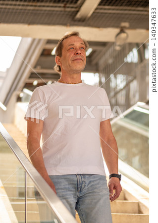 Portrait of a 55 year old man against modern architecture with glass railings and stairs. Portrait of a 55 year old man against modern architecture with glass railings and stairs. 140347633