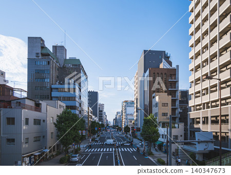 從人行天橋上可以看到一條主要城市道路，道路兩旁林立著辦公大樓和公寓大樓。 140347673