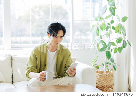 A man looking at his smartphone in the living room A man looking at his smartphone in the living room 140348670