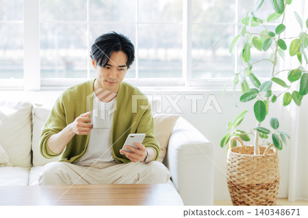 A man looking at his smartphone in the living room A man looking at his smartphone in the living room 140348671