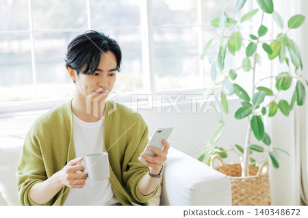 一個男人在客廳看著他的智慧型手機 140348672