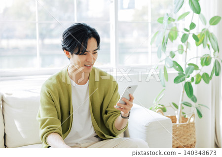 一個男人在客廳看著他的智慧型手機 140348673