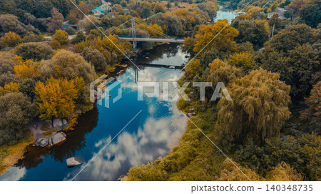 Aerial view of a winding river flowing through a lush forest with a bridge overhead Aerial view of a winding river flowing through a lush forest with a bridge overhead 140348735