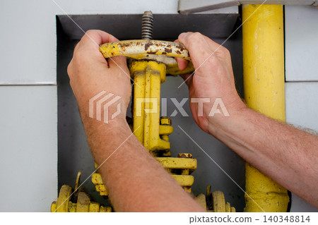Energy crisis and gas supply management, hands turning yellow industrial valve for natural gas pipeline control and regulation. Energy crisis and gas supply management, hands turning yellow industrial valve for natural gas pipeline control and regulation. 140348814