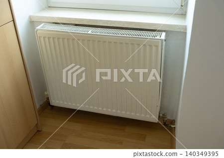 White metal heating radiator under windowsill. Central heating system. White metal heating radiator under windowsill. Central heating system. 140349395