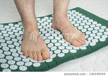 Man standing on acupressure massage mat barefoot. 140349450
