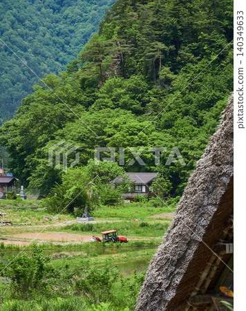 A scene of the gassho-zukuri houses and farm machinery working in the rice paddies of Shirakawa-go, a World Heritage site and popular tourist spot in early summer. A scene of the gassho-zukuri houses and farm machinery working in the rice paddies of Shirakawa-go, a World Heritage site and popular tourist spot in early summer. 140349633