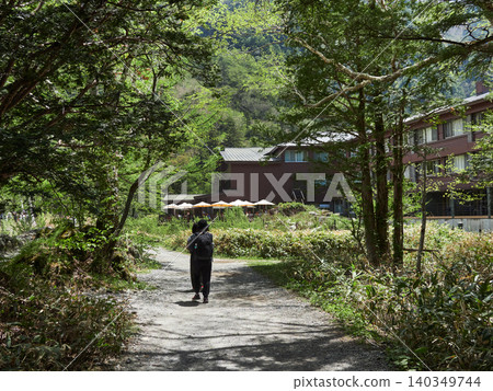 A scene of tourists walking along the trails of Kamikochi, a popular spring tourist spot, and the appearance of a hotel building. A scene of tourists walking along the trails of Kamikochi, a popular spring tourist spot, and the appearance of a hotel building. 140349744