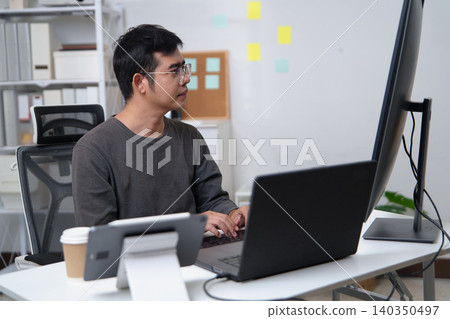 Focused Programmer Working on Code at a Desk Setup in a Professional Environment Focused Programmer Working on Code at a Desk Setup in a Professional Environment 140350497