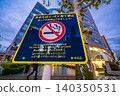 Sign in front of Kayabacho Station: No smoking while walking or littering in Tokyo's urban landscape. 140350531