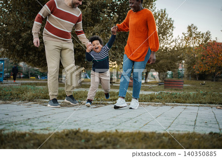 Happy family walking in park holding child hands Happy family walking in park holding child hands 140350885