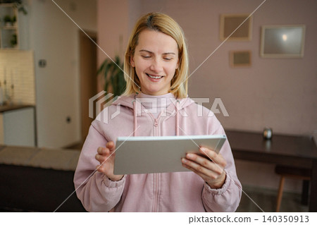 Young adult woman using digital tablet at home smiling Young adult woman using digital tablet at home smiling 140350913