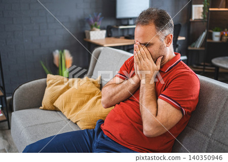 Man sitting alone at home looking sad and distraught Man sitting alone at home looking sad and distraught 140350946