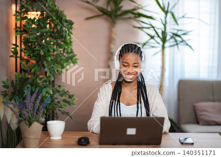 Young adult woman enjoying music remote working at home 140351171