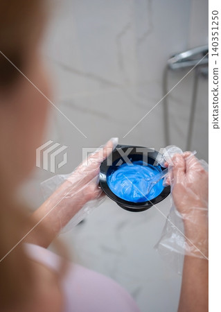 Woman preparing blue hair dye in bathroom Woman preparing blue hair dye in bathroom 140351250